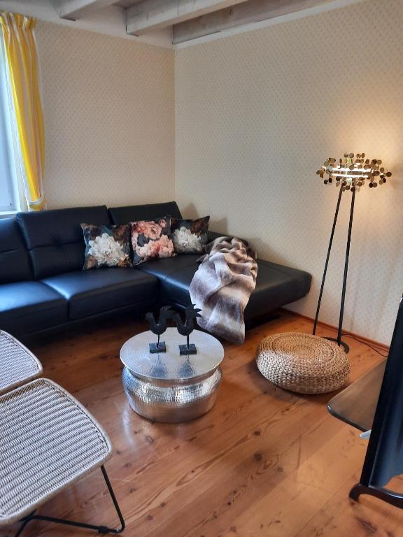 a living room with a black couch and a table at Das Landhaus Oberstdorf in Oberstdorf