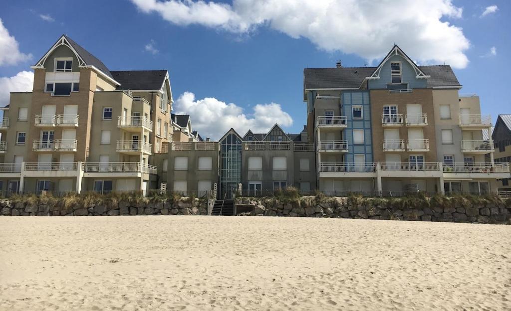 - un grand bâtiment sur la plage à côté du sable dans l'établissement Les Villas d 'Opale, à Berck-sur-Mer