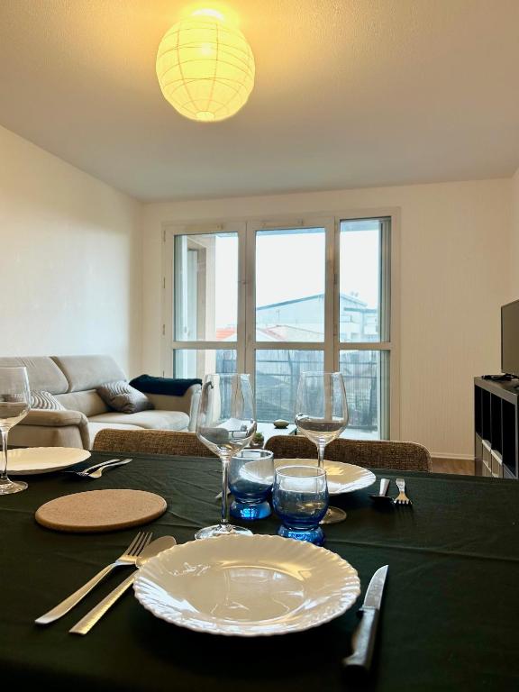 une table de salle à manger avec des assiettes et des verres dessus dans l'établissement Bois d 'Ormeau - T3 - terrace - quiet - open view, à Toulouse
