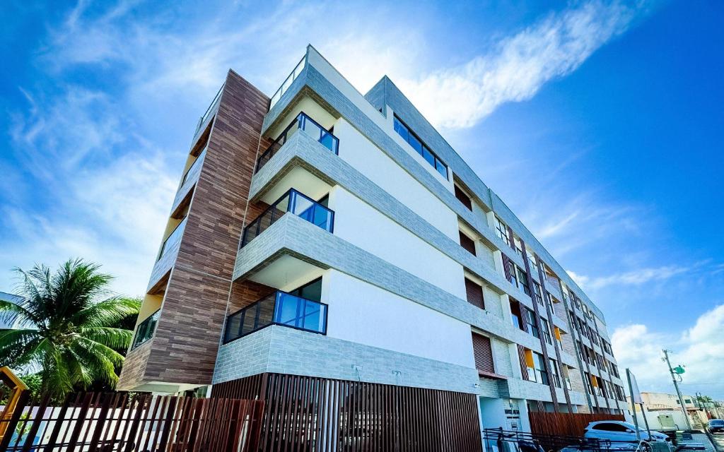 um prédio alto e branco com uma cerca na frente em Mare Alta Tamandaré em Tamandaré