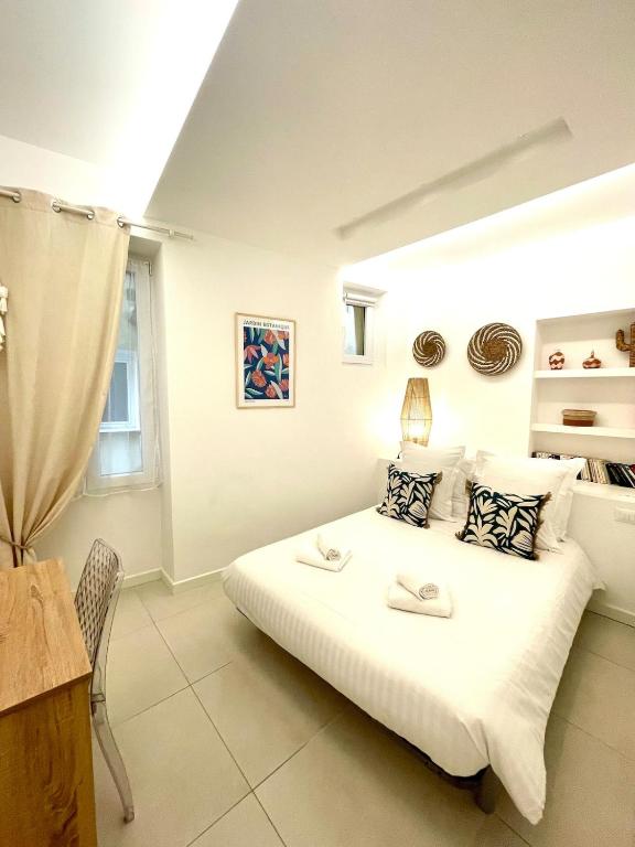 une chambre avec un grand lit blanc avec une fenêtre dans l'établissement Le Cap, beau trois pièces au coeur de la vieille ville, à Menton