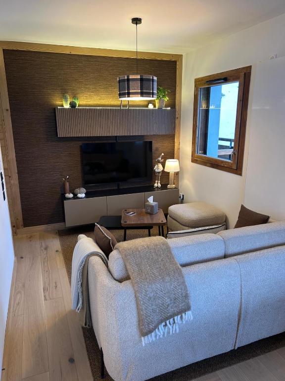 un salon avec un canapé bleu et une télévision dans l'établissement NOUVEAU appartement neuf 4 à 6 personnes dans la station du Chinaillon, Grand-Bornand, au Chinaillon