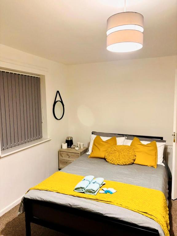 a bedroom with a bed with yellow pillows and a yellow blanket at CityZen - serviced accomodation in Birmingham