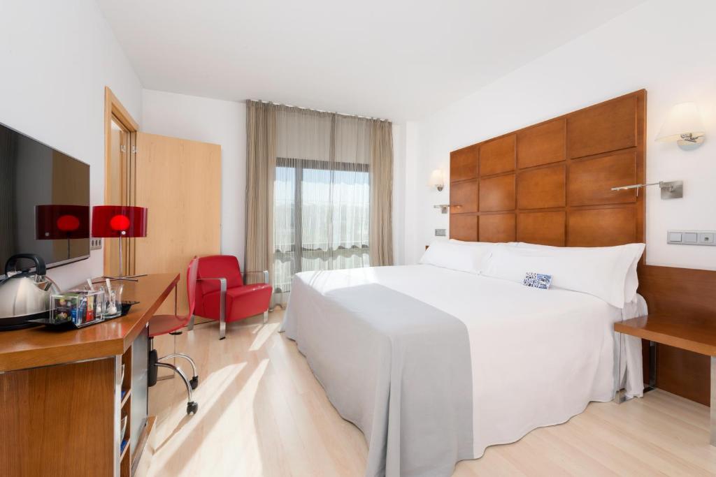Habitación de hotel con cama blanca grande y escritorio. en Hotel Zentral Ave, en Zaragoza