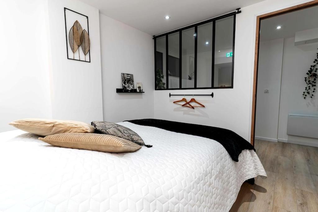 une chambre avec un lit blanc avec deux oreillers dessus dans l'établissement Appartement atypique et cosy centre-ville, à Strasbourg