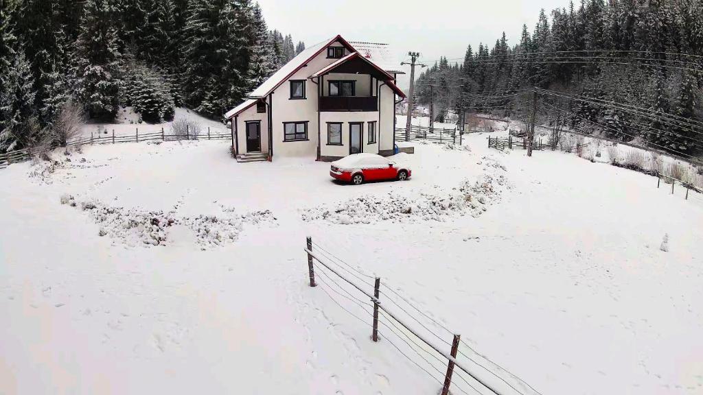 a red car parked in front of a house in the snow at The Froggies in Gura Negri