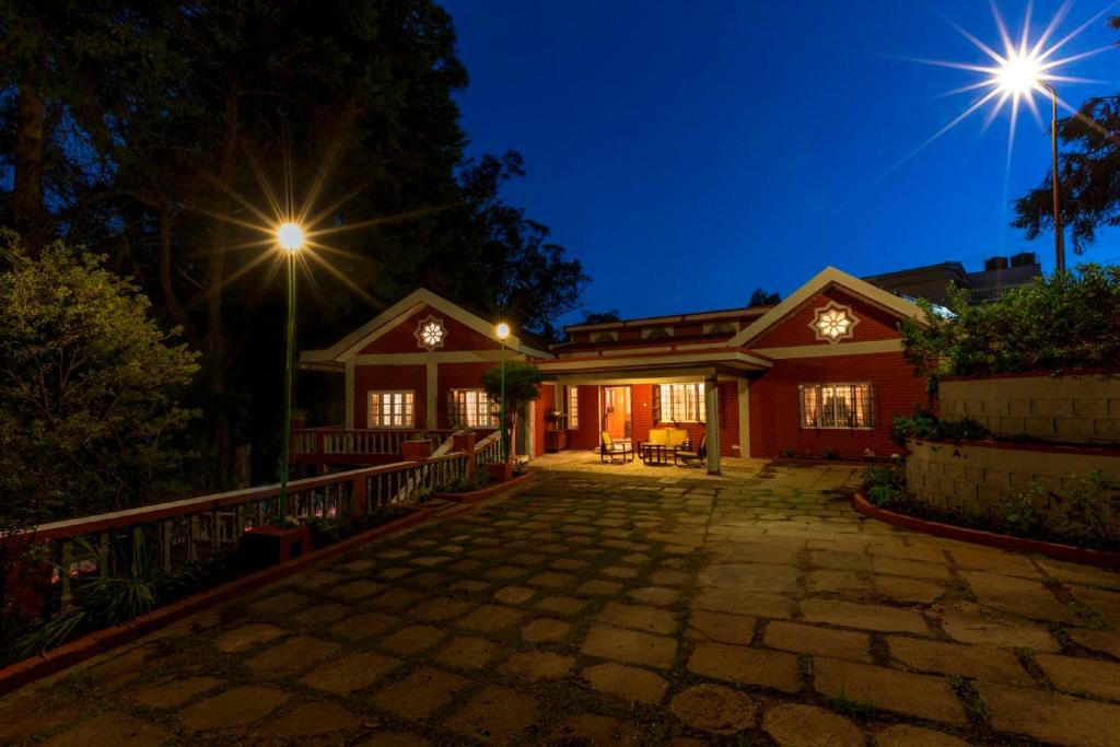 uma casa à noite com duas luzes acesas em The Red House em Ooty