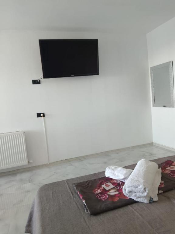Habitación blanca con cama y TV en la pared. en Garsonieră confort 1, en Buzau