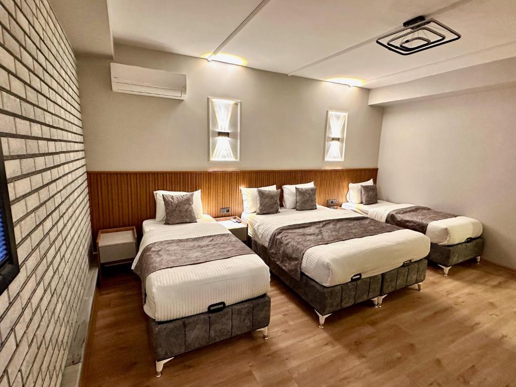 a room with three beds in it with windows at Skymoon Istanbul Airport Hotel in Arnavutköy