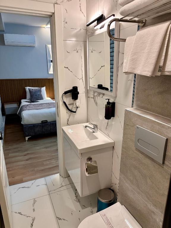 a bathroom with a sink and a mirror and a bed at Skymoon Istanbul Airport Hotel in Arnavutköy
