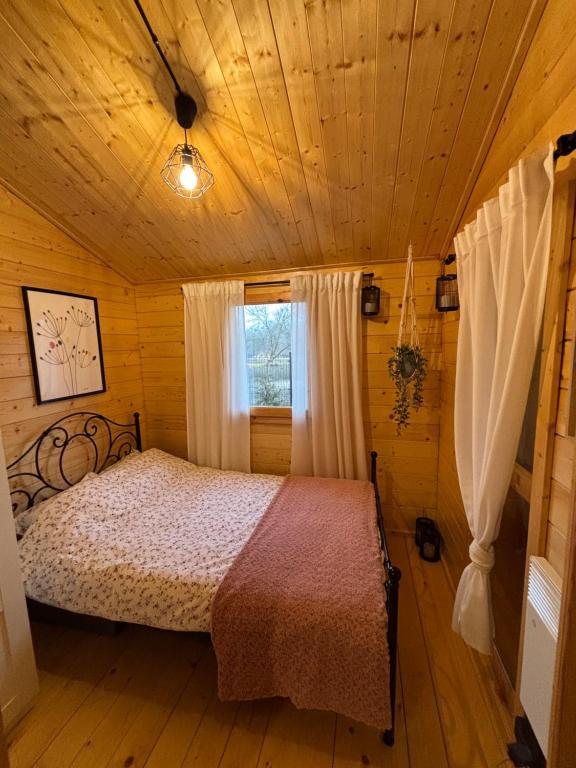 a bedroom with a bed in a wooden cabin at Domek letniskowy z jacuzzi nad rzeką Bzurą in Żuków
