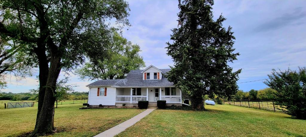 a white house in a field with two trees at Warrensburg, UCM, Whiteman AFB, KC Chiefs, Wedding Venue, Bring your Pet, Secluded Farmhouse in Centerview