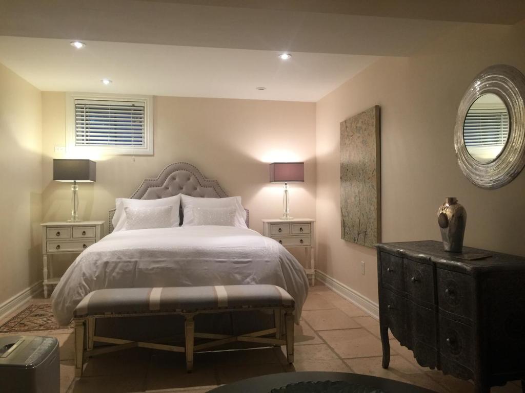 a bedroom with a bed and two tables and a mirror at Lion's Head B&B in Niagara Falls