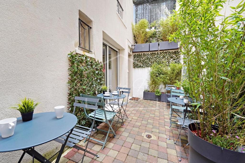 un patio avec tables, chaises et plantes dans l'établissement Charmant appartement 23m2 à Pantin, à Pantin