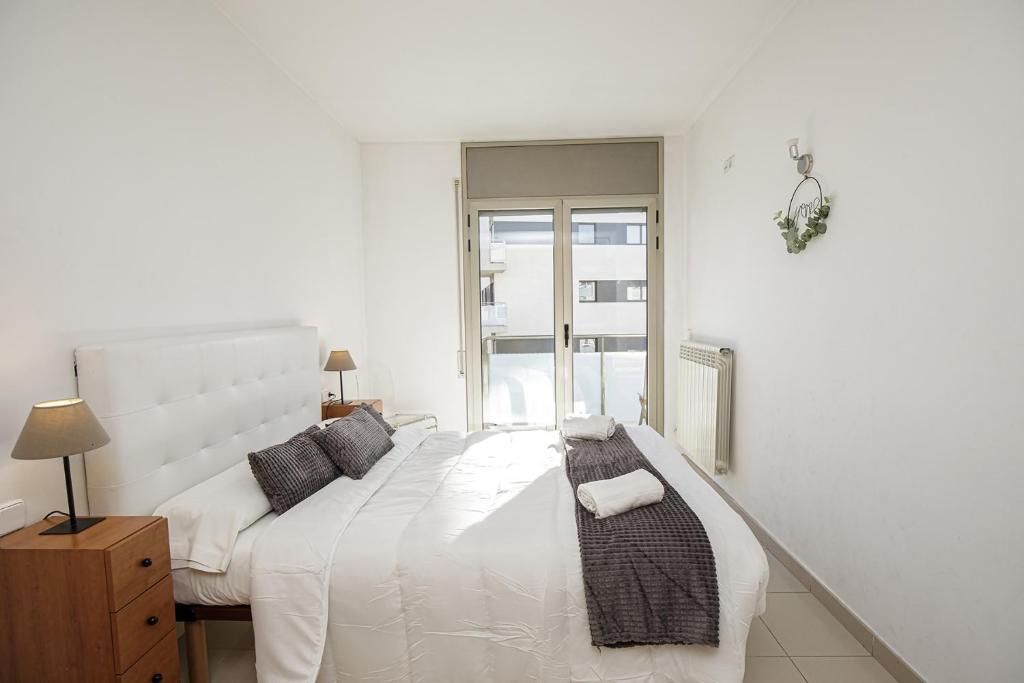 una camera da letto bianca con un letto grande e una finestra di Apartamento Riu Fluvià Girona a Girona