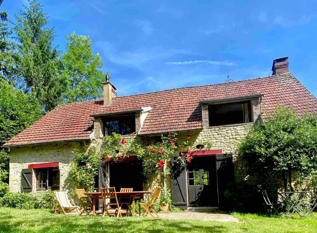 une maison en pierre avec une table et des fleurs. dans l'établissement Maison dans le Perche type cottage, à Saint-Agnan-sur-Sarthe