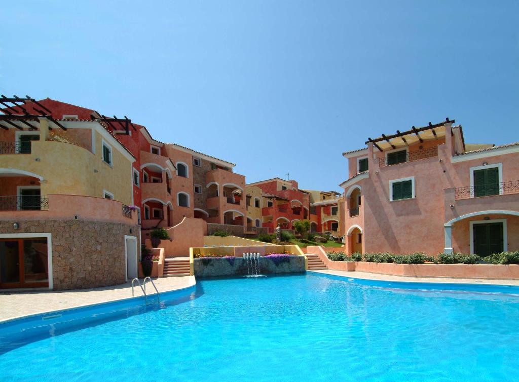 une grande piscine en face de certains bâtiments dans l'établissement La Reggia Di Nausicaa, à Santa Teresa Gallura