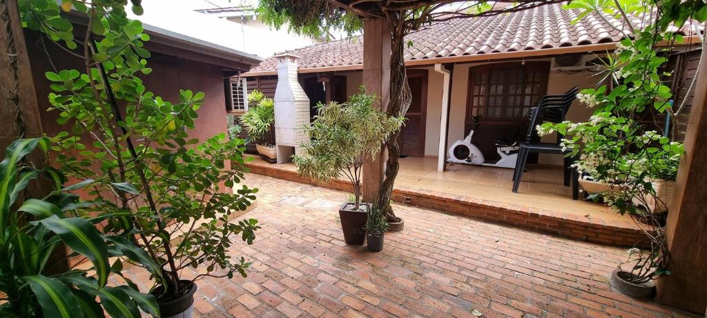 a house with a brick patio with trees and plants at Casa no centro aproveite o melhor de Foz in Foz do Iguaçu