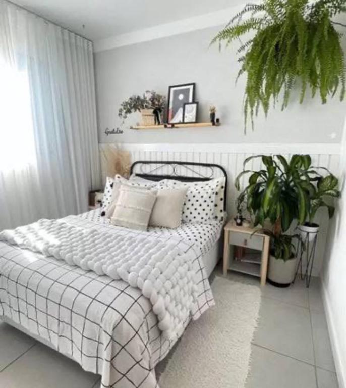 a bedroom with a bed with pillows and a plant at Apartamento encantador in La Victoria