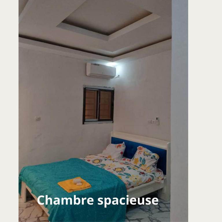een kleine slaapkamer met een bed met een groene deken bij Fôhundi home in Abidjan