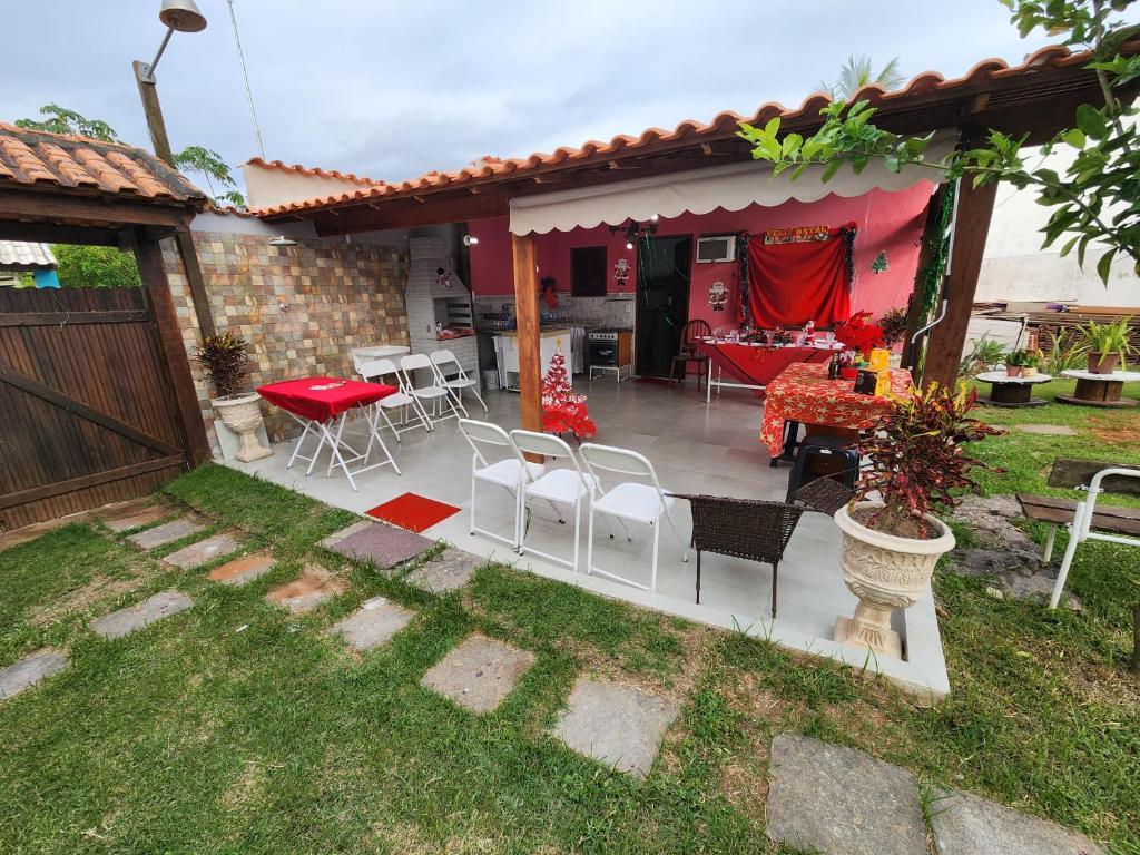 a patio with chairs and a table in a yard at Casa da Dinda à 650m da praia de Itaúna in Saquarema