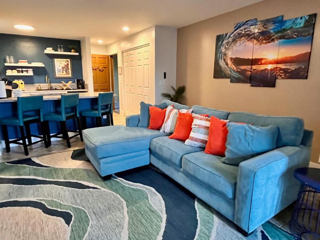 Una sala de estar con un sofá azul y una cocina. en Holualoa Gardens 104, en Kailua-Kona