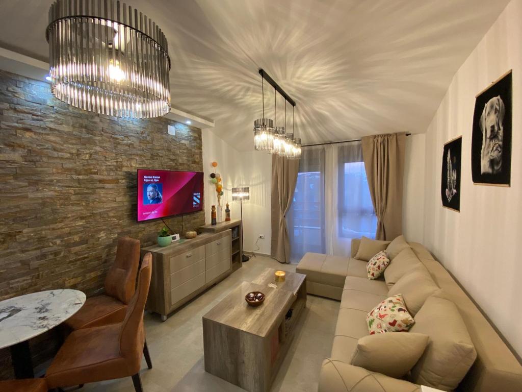 un soggiorno con divano, tavolo e TV di Apartman Izvor tišine a Divčibare