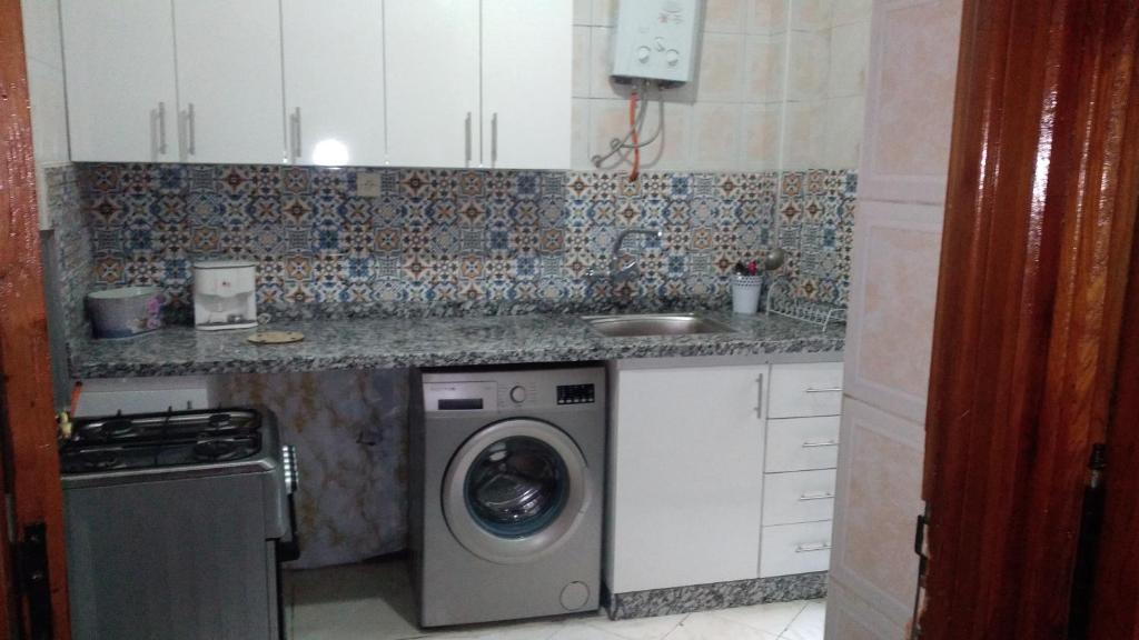 a kitchen with a washing machine and a sink at appartement central plein d’expérience in Martil