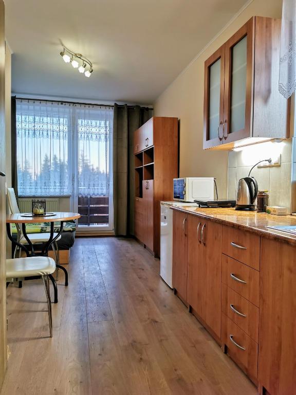 a kitchen with wooden cabinets and a table and a dining room at Apartman pri boroviciach in Štrbské Pleso