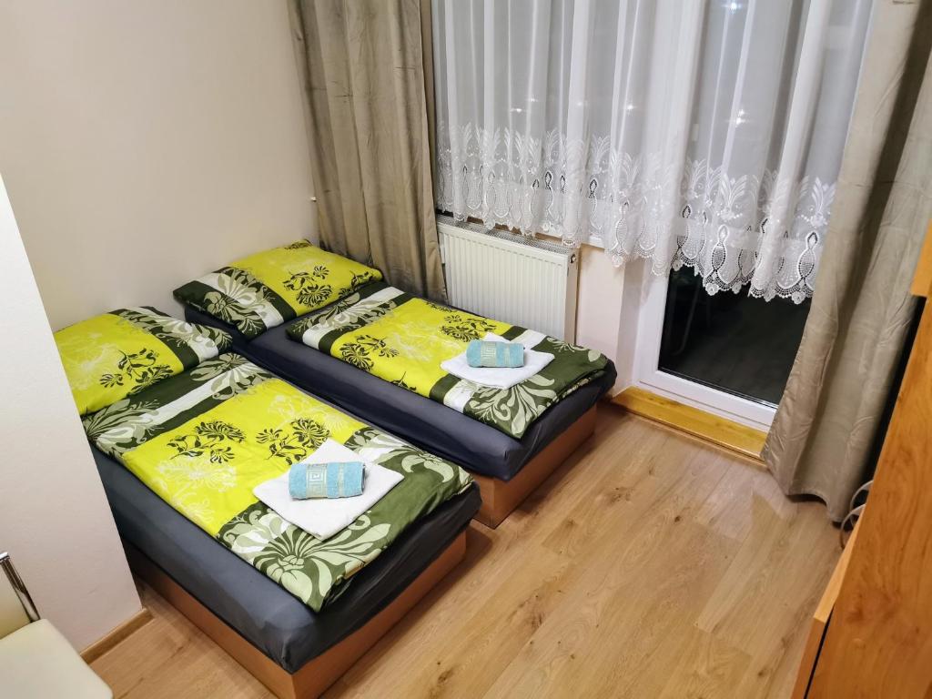 two beds in a small room with a window at Novozrekonstruovany apartman pri boroviciach in Štrbské Pleso