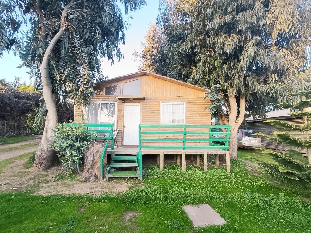 two green benches in front of a house at Cabañas Ana María Pichilemu in Pichilemu