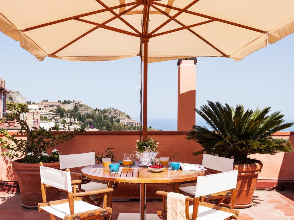 einen Tisch und Stühle mit Sonnenschirm auf einer Terrasse in der Unterkunft San Domenico Apartment in Taormina