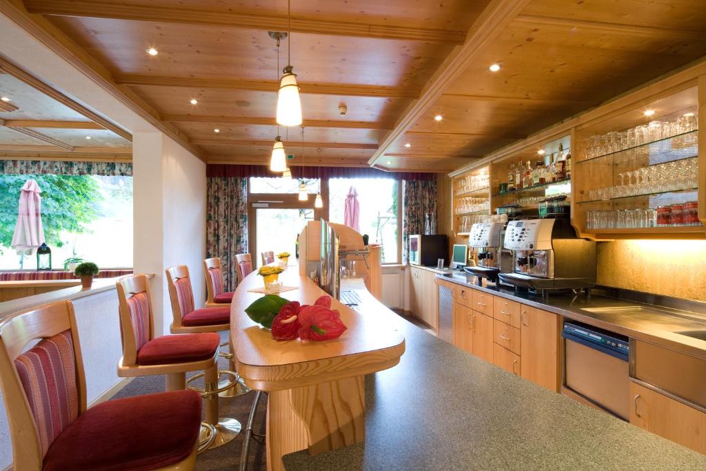 a kitchen with a counter with chairs and a counter top at Hotel Bergland in Pertisau