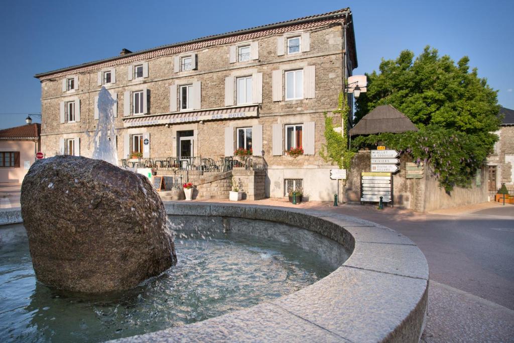een grote stenen fontein voor een gebouw bij Hotel Restaurant Le Sully in Saint-Saud-Lacoussière