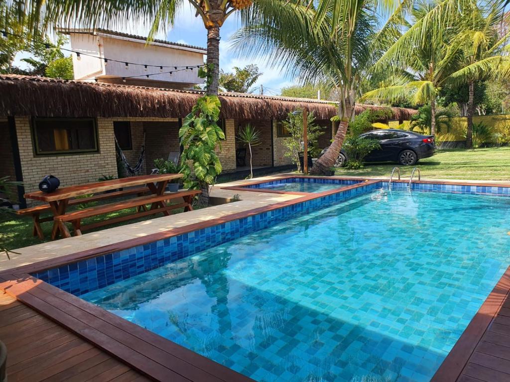 a swimming pool with a bench and a house at Beija Flor in Pipa