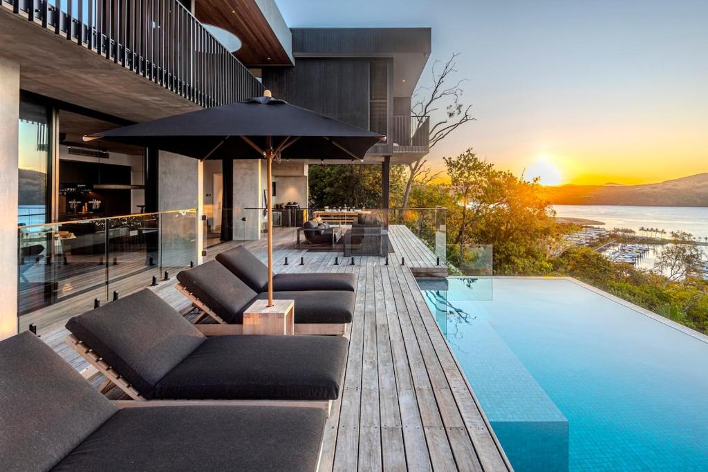 una casa con piscina con sillas y sombrilla en Haven House at Hamilton Island, en Hamilton Island