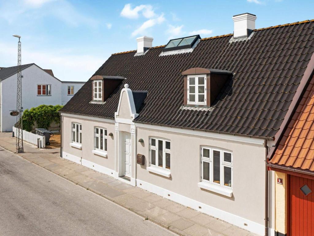 a white house with a black roof on a street at Spacious Retreat in Lokken - By Traum Ferienwohnungen in Løkken