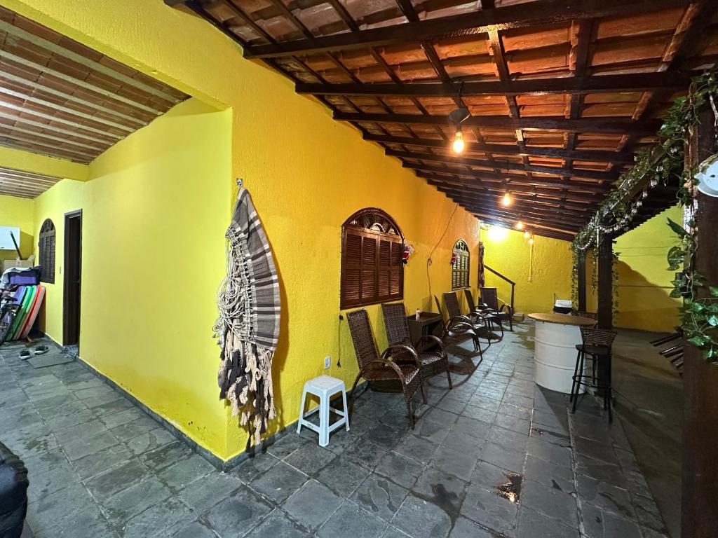 a room with a yellow wall with a table and chairs at Via sol rio das ostras in Rio das Ostras