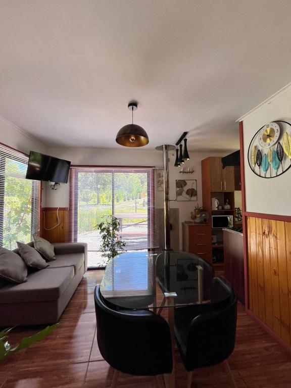 ein Wohnzimmer mit Sofa und Glastisch in der Unterkunft Cabaña estilo mediterránea in Pucón
