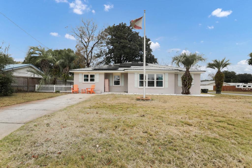 a white house with a flag in the yard at Ocean - 5 Beds Retreat with Pickleball, Arcade, Grill & Beach Access! in Fort Walton Beach