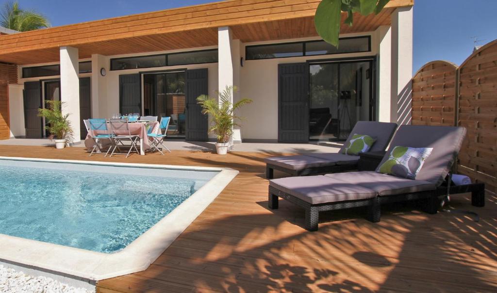un patio con mesa y sillas y una piscina en Villa Saline, en La Saline-Les-Bains