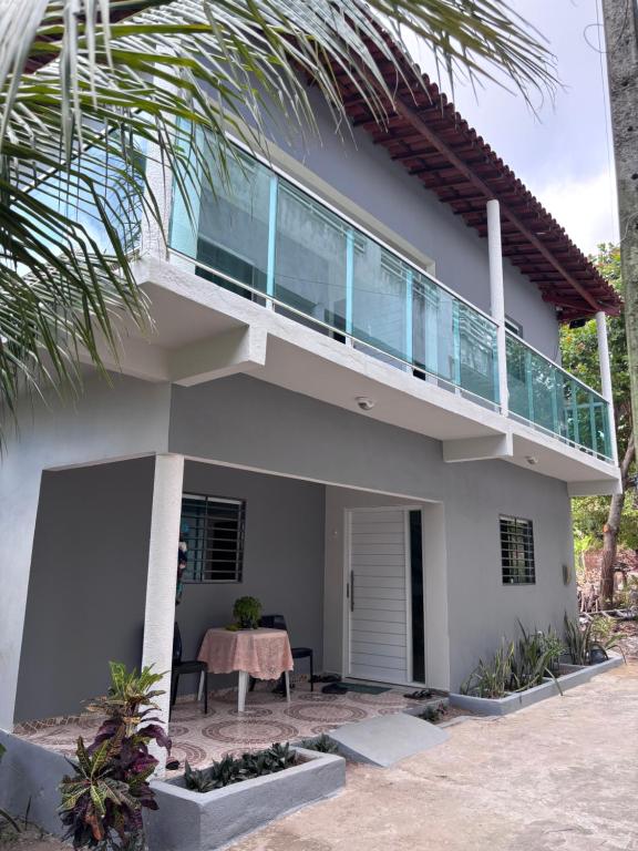 a house with a balcony with a table in front of it at Residência Naiote in Japaratinga