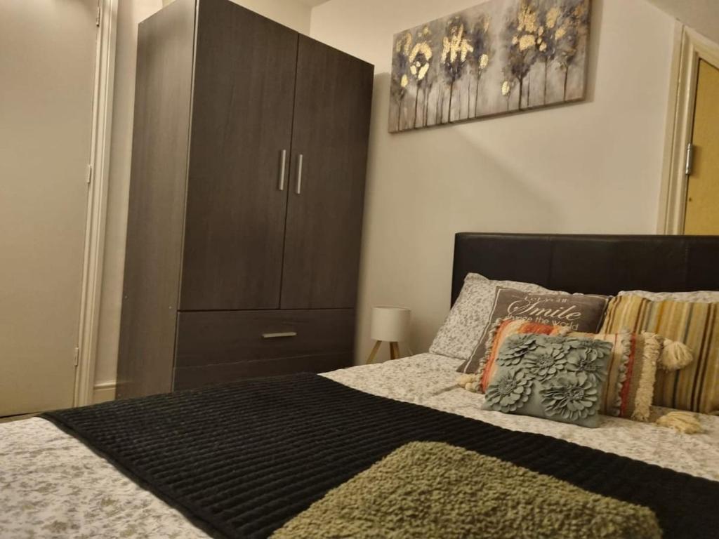 a bedroom with a bed with a brown cabinet at Loft Flat, near Hampton Court Palace, Free Parking in West Molesey