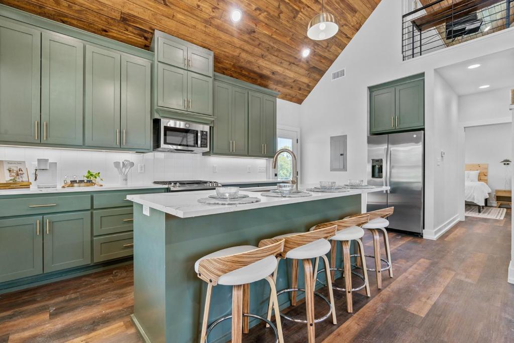 a kitchen with green cabinets and a large island with bar stools at The June Hot tub with king beds on 2 acres in Hot Springs