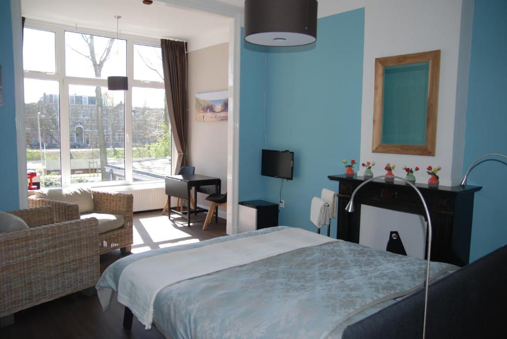ein blaues Schlafzimmer mit einem Bett und einem Wohnzimmer in der Unterkunft Bed & Breakfast Obrechtstraat in Den Haag