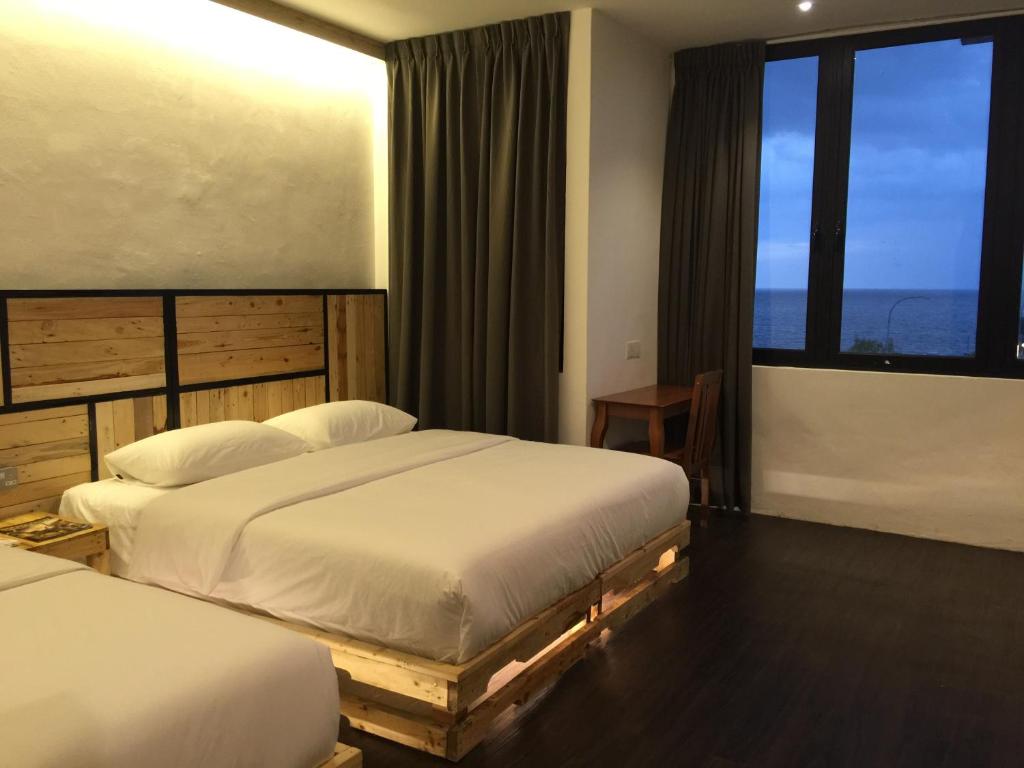 two beds in a hotel room with windows at The Oikos Hotel in Pontian Kecil