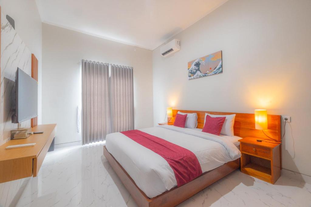 una camera da letto bianca con un letto e una televisione di The Bingin Sari Jimbaran a Jimbaran