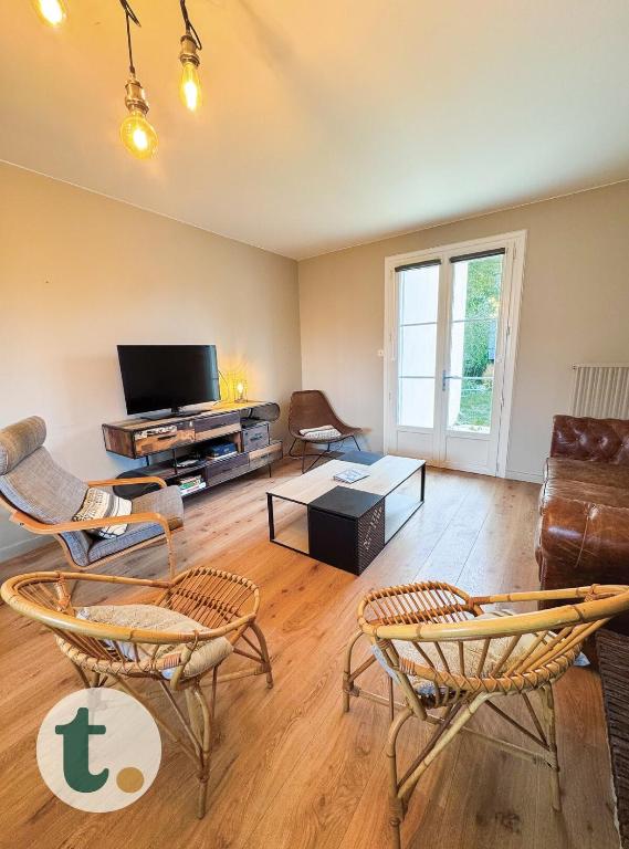 un salon avec des chaises et une télévision à écran plat dans l'établissement Tranquiloue - Grande maison spacieuse - PuyduFou, aux Herbiers