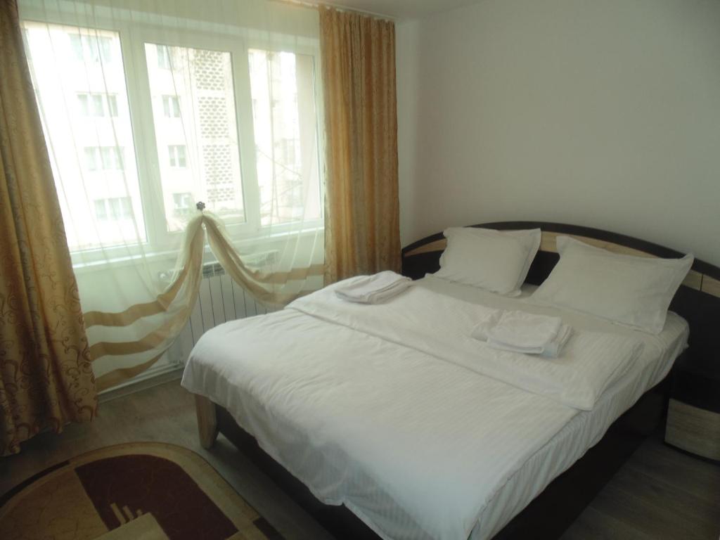 Schlafzimmer mit einem Bett mit weißer Bettwäsche und einem Fenster in der Unterkunft Lary apartament in Suceava