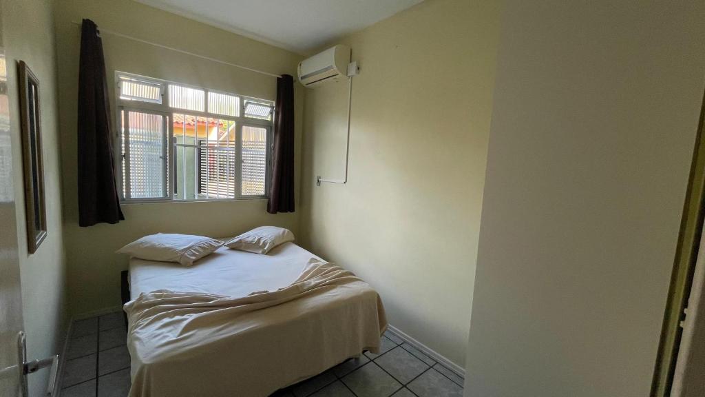 um pequeno quarto com uma cama e uma janela em Recanto do Martins em Florianópolis